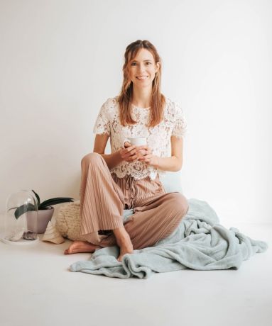 lachend meisje die zit op deken met kopje in haar handen